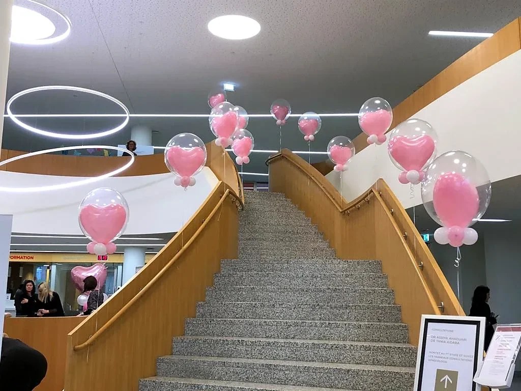 Pink October decoration: bubble balloons with pink hearts hung along a staircase in a hall, Luxembourg